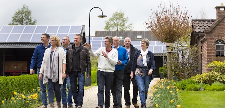 Een groep mensen loopt door een straat in Nijeveen. Op de achtergrond staan huizen met zonnenpanelen.