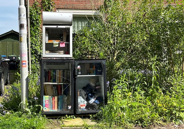 Een minibibliotheek in een groene omgeving.