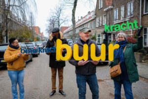 Vier mensen staan in een straat en hebben 'Buurkracht' letters vast.
