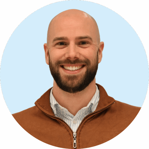 Portretfoto van Buurkracht buurtbegeleider Rutger, van schouders tot boven, genomen voor een lichtblauwe achtergrond.