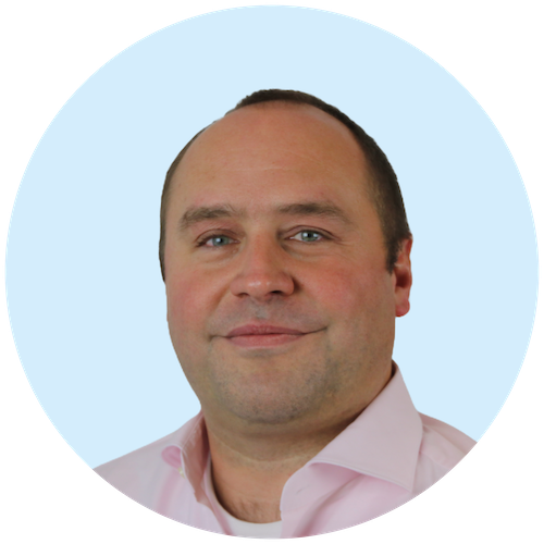 Portretfoto van Buurkracht directeur Ben, van schouders tot boven, genomen voor een lichtblauwe achtergrond.