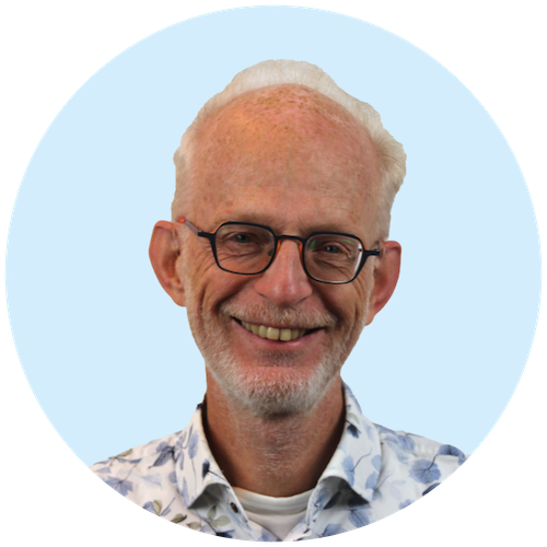 Portretfoto van Buurkracht buurtbegeleider Cees, van schouders tot boven, genomen voor een lichtblauwe achtergrond.