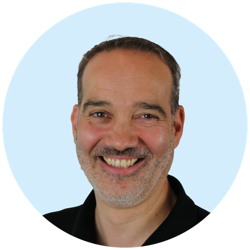 Portretfoto van Buurkracht marketeer Djoera, van schouders tot boven, genomen voor een lichtblauwe achtergrond.