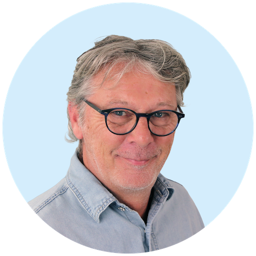 Portretfoto van Buurkracht buurtbegeleider Floris, van schouders tot boven, genomen voor een lichtblauwe achtergrond.