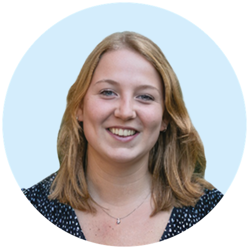 Portretfoto van Buurkracht buurtbegeleider Isabel, van schouders tot boven, genomen voor een lichtblauwe achtergrond.