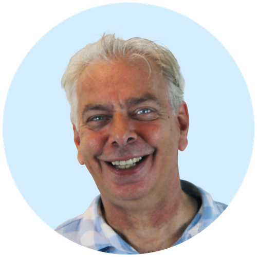 Portretfoto van Buurkracht buurtbegeleider Jos, van schouders tot boven, genomen voor een lichtblauwe achtergrond.