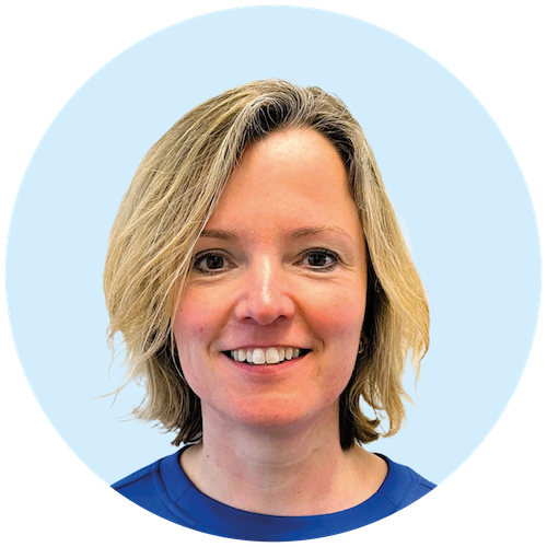 Portretfoto van Buurkracht buurtbegeleider Sylvia, van schouders tot boven, genomen voor een lichtblauwe achtergrond.