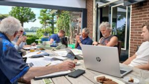 De buurtteams uit Beilen en Westerbork werken samen aan een tafel vol met papier en laptops.