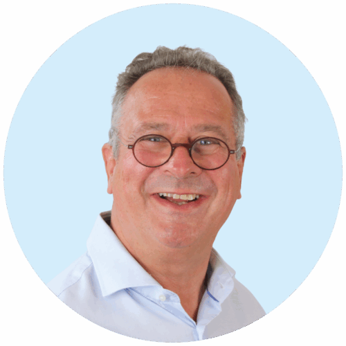 Portretfoto van Buurkracht buurtbegeleider Johan, van schouders tot boven, genomen voor een lichtblauwe achtergrond.