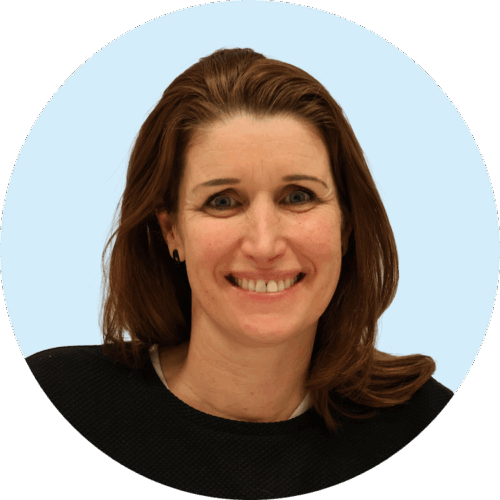 Portretfoto van Buurkracht buurtbegeleider Kitty, van schouders tot boven, genomen voor een lichtblauwe achtergrond.