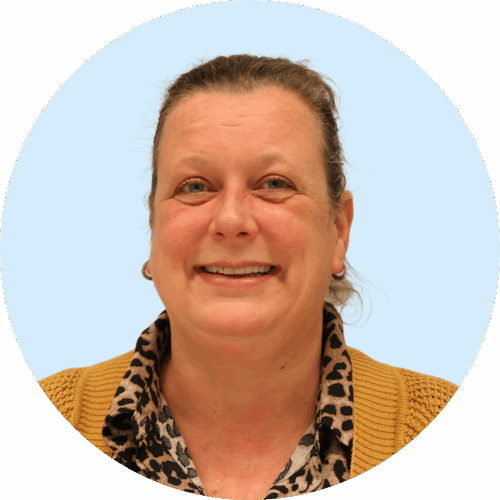 Portretfoto van Buurkracht buurtbegeleider Marieke, van schouders tot boven, genomen voor een lichtblauwe achtergrond.