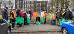 Een groep bewoners heeft afvalprikkers en vuilniszakken vast en poseren voor een banner tijdens de Priknick in Boxtel.