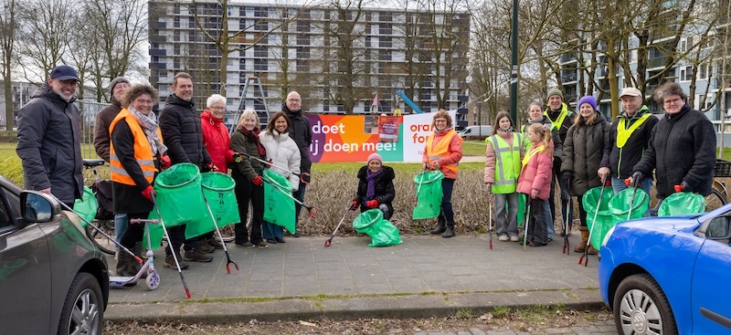 Een groep bewoners heeft afvalprikkers en vuilniszakken vast en poseren voor een banner tijdens de Priknick in Boxtel.